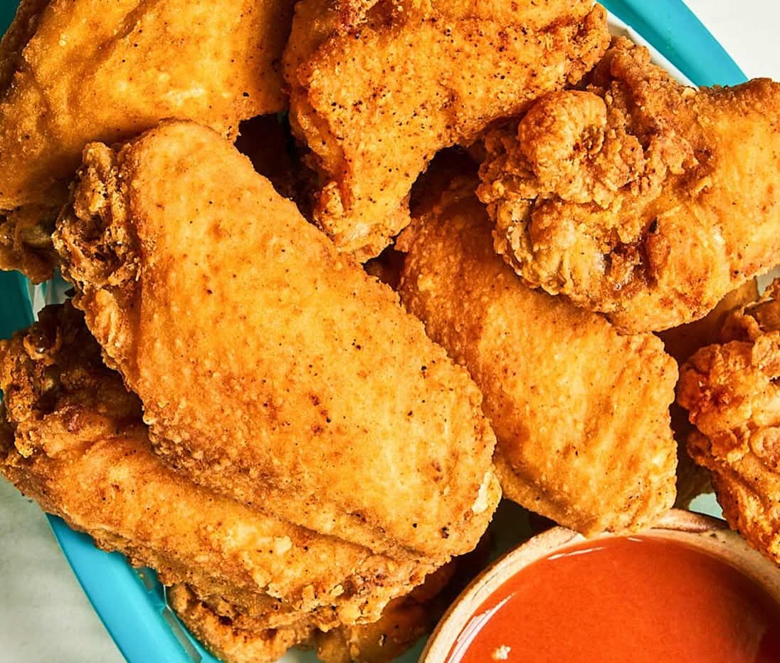 Golden hand-breaded classic fried wings with hot sauce